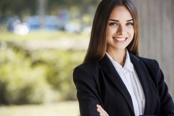 Cropped image of beautiful smiling business woman outdoors. Background is blurred.
