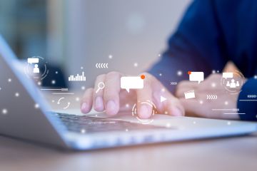 a person typing on a laptop with various digital icons hovering above the keyboard